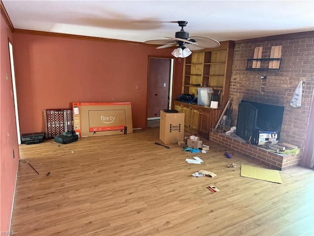 unfurnished living room featuring wood finished floors, ceiling fan, ornamental molding, built in shelves, and a fireplace
