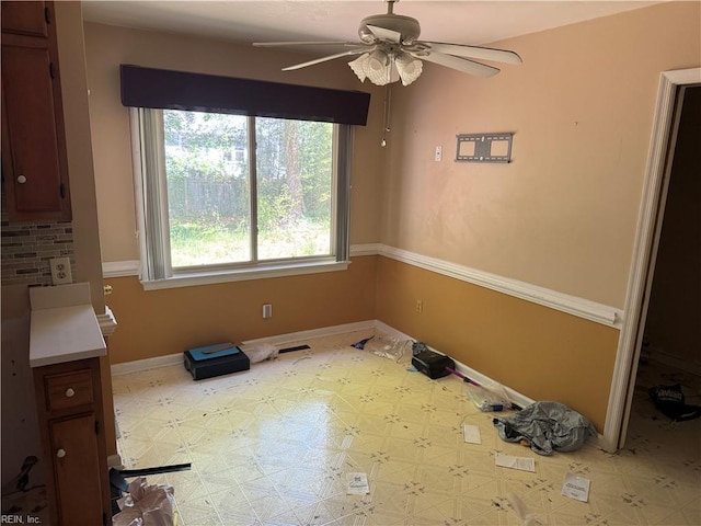unfurnished dining area featuring a ceiling fan, baseboards, and light floors
