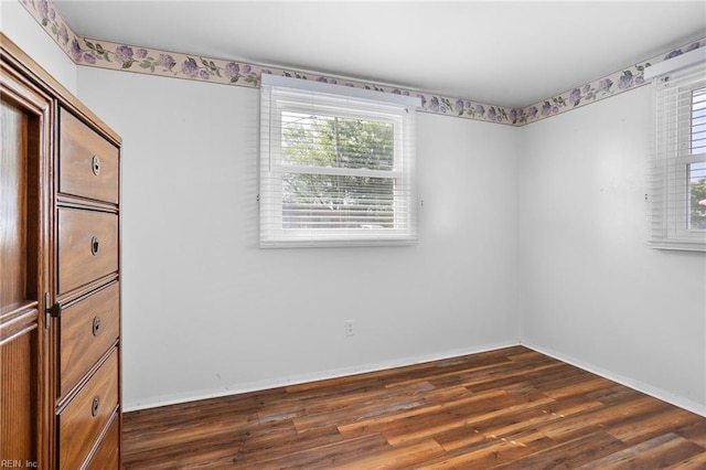 unfurnished room featuring dark wood-style flooring and baseboards