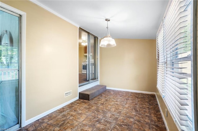 unfurnished dining area with plenty of natural light, baseboards, and stone finish floors