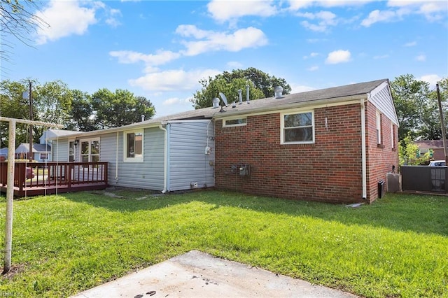 rear view of house with a deck, brick siding, and a yard