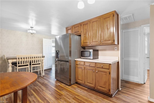 kitchen featuring stainless steel appliances, light wood-type flooring, light countertops, and brown cabinets