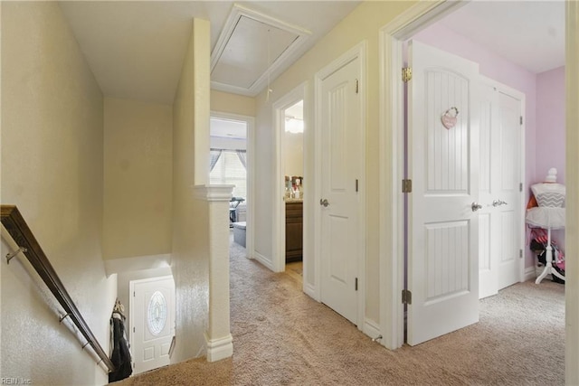 corridor featuring light carpet and attic access