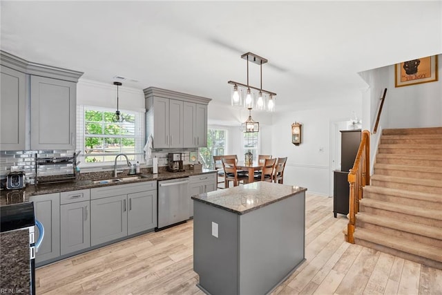 kitchen featuring gray cabinetry, appliances with stainless steel finishes, a sink, and light wood-style floors