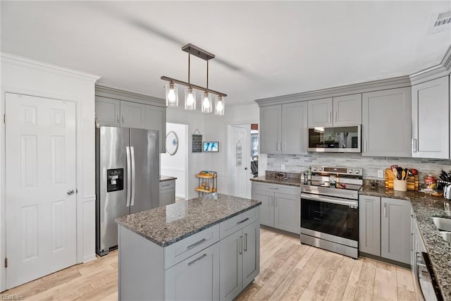 kitchen featuring stainless steel appliances, gray cabinetry, crown molding, decorative backsplash, and light wood-style flooring