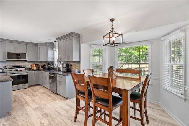 dining area featuring light wood-type flooring, a chandelier, and baseboards