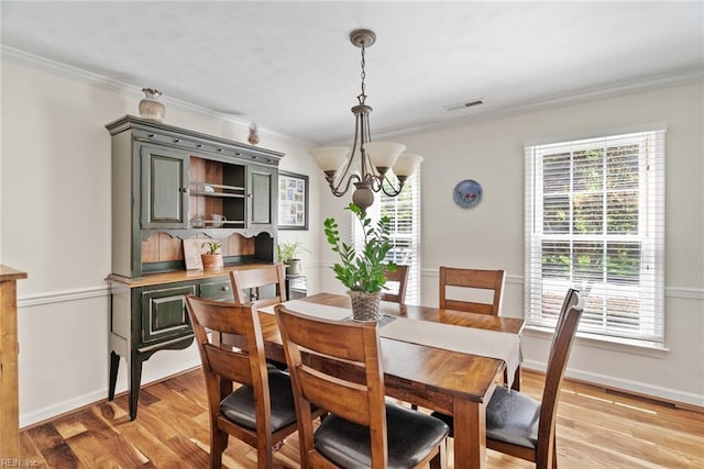 dining space featuring a chandelier, healthy amount of natural light, ornamental molding, and light wood-style floors