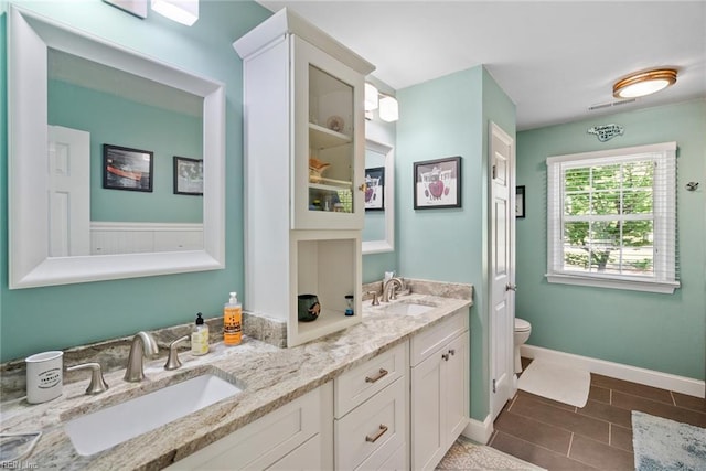 bathroom featuring double vanity, toilet, and baseboards