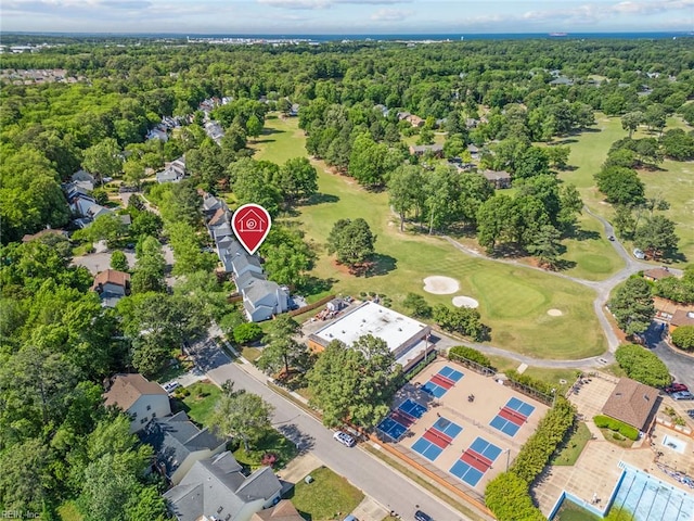 aerial view of property and surrounding area featuring a golf course and nearby suburban area