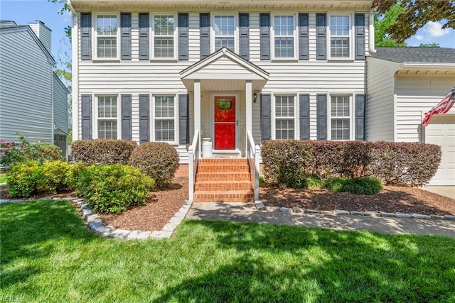 colonial house featuring an attached garage and a front lawn