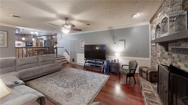 living room featuring crown molding, a ceiling fan, dark wood-style flooring, a brick fireplace, and a textured ceiling