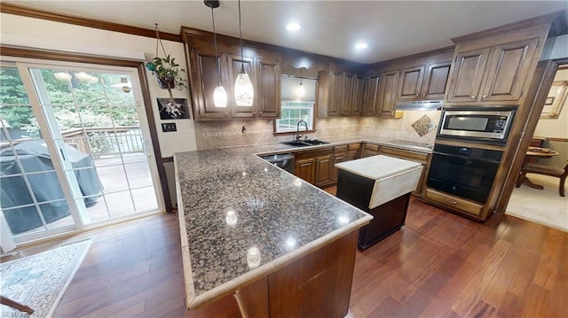 kitchen featuring appliances with stainless steel finishes, a sink, dark wood-type flooring, tasteful backsplash, and a center island