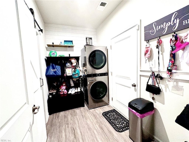 3432 Foxglove Dr, Toano, VA 23168 - clothes washing area featuring stacked washer and clothes dryer, wood finished floors, and a barn door