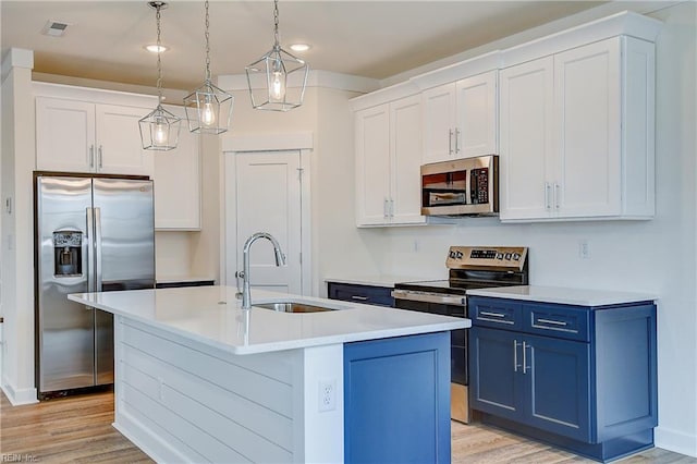 kitchen featuring a sink, light wood-style flooring, blue cabinetry, and appliances with stainless steel finishes