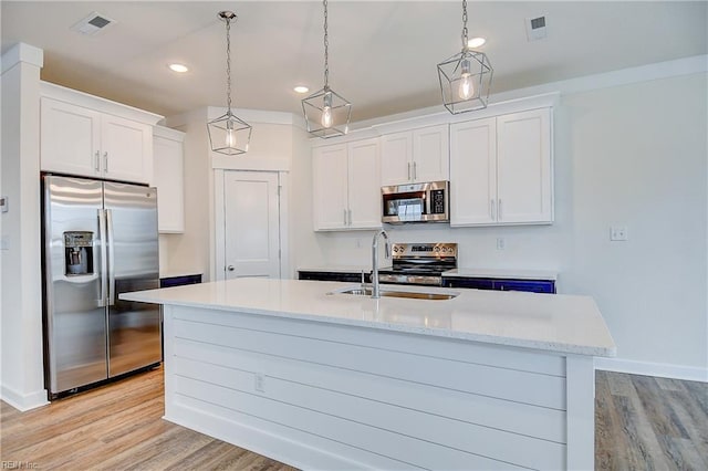 kitchen with light wood finished floors, a sink, white cabinets, appliances with stainless steel finishes, and recessed lighting