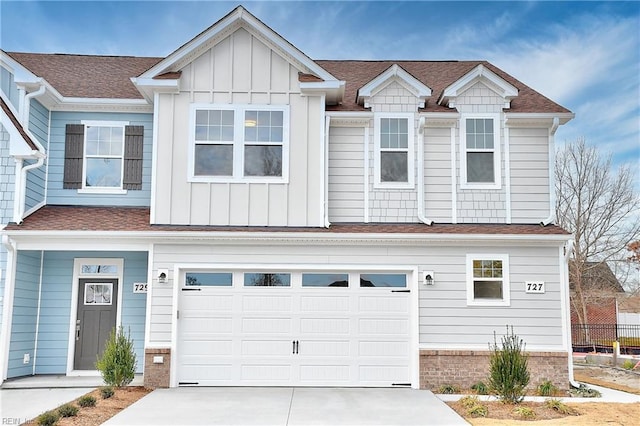multi unit property with driveway, board and batten siding, an attached garage, and roof with shingles