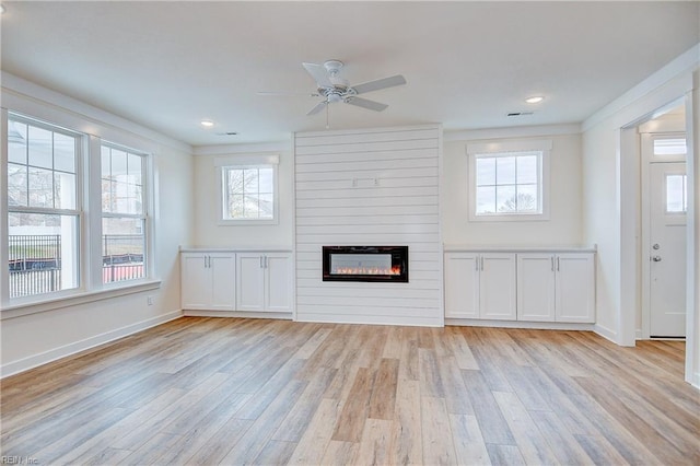 unfurnished living room featuring light wood finished floors, baseboards, ceiling fan, and plenty of natural light