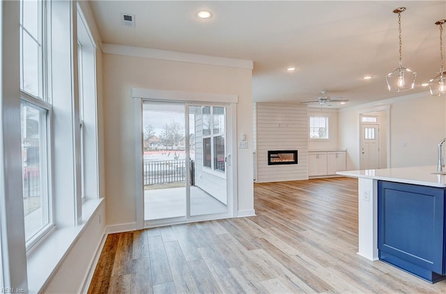 kitchen featuring recessed lighting, light wood finished floors, blue cabinetry, light countertops, and a large fireplace