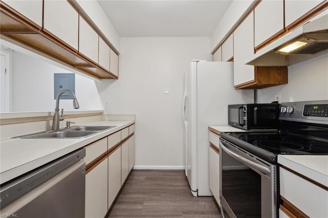 kitchen with stainless steel appliances, a sink, light countertops, dark wood-type flooring, and under cabinet range hood
