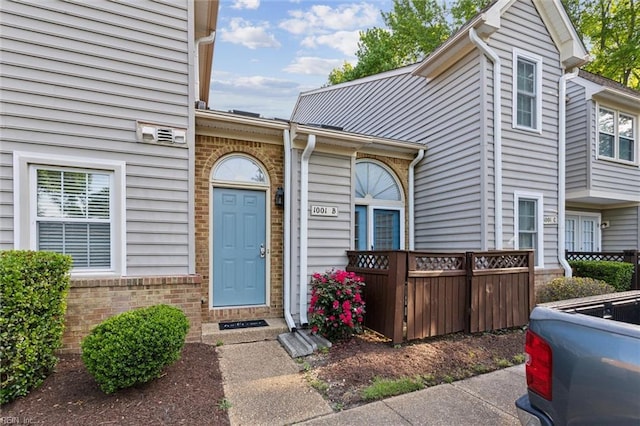 entrance to property featuring brick siding and fence