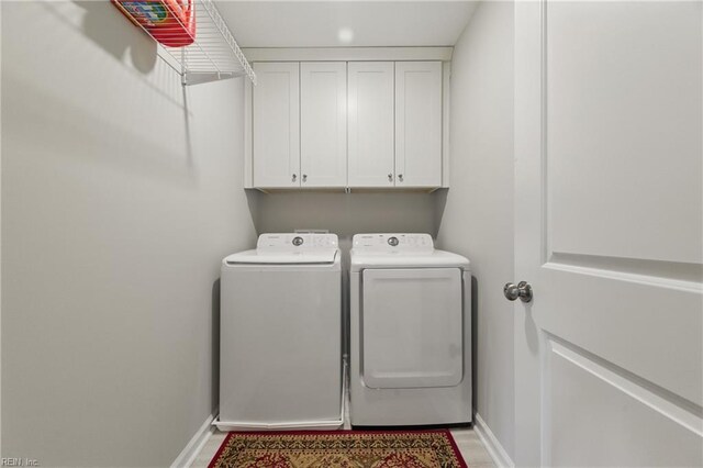 washroom featuring independent washer and dryer, cabinet space, baseboards, and light wood-style floors