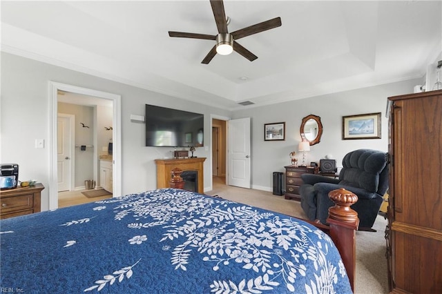 bedroom with a raised ceiling, carpet flooring, crown molding, a ceiling fan, and connected bathroom