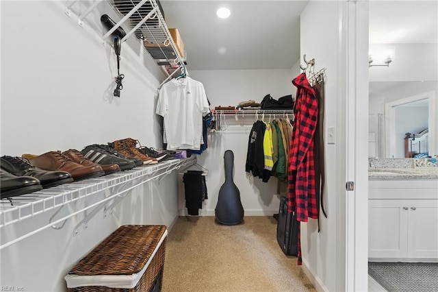 walk in closet with light carpet and a sink