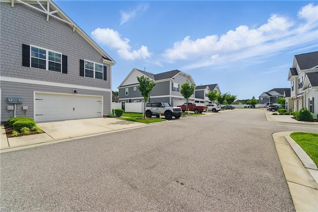 view of asphalt road featuring a residential view, curbs, and sidewalks