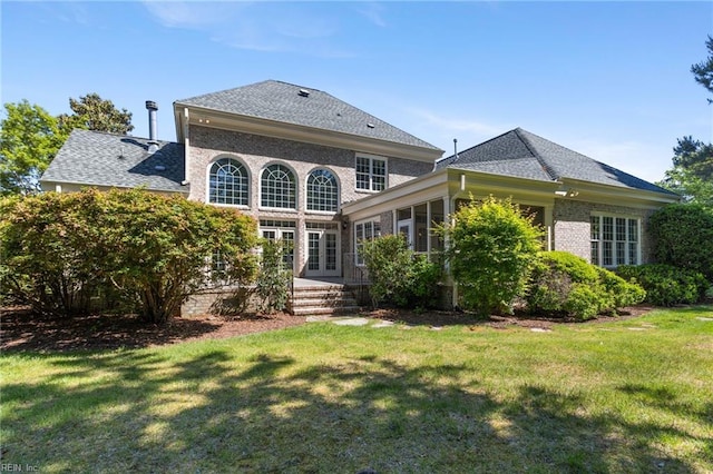 back of house with a lawn, a shingled roof, french doors, and brick siding