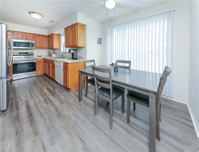 1242 Woods Edge Cir, Suffolk, VA 23434 - kitchen with stainless steel appliances, light wood-type flooring, light countertops, a ceiling fan, and a sink