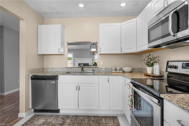 kitchen with appliances with stainless steel finishes, a sink, recessed lighting, white cabinetry, and baseboards