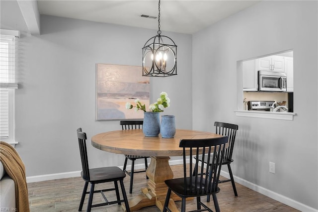 dining room with wood finished floors, a chandelier, and baseboards