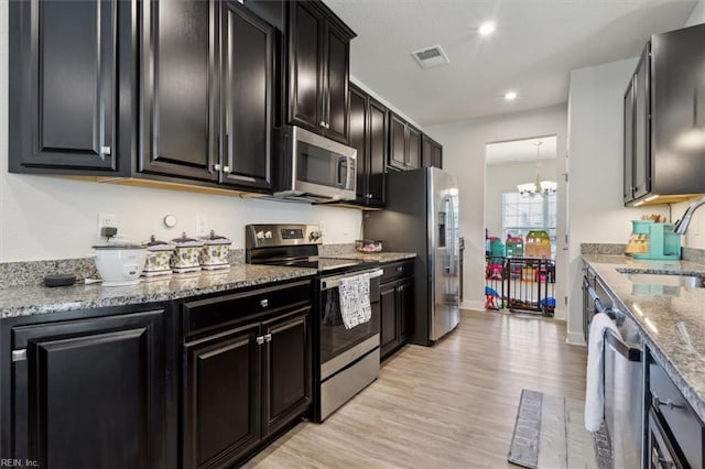 909 Porte Crayon St, Chesapeake, VA 23323 - kitchen featuring appliances with stainless steel finishes, a sink, dark cabinets, a chandelier, and light wood finished floors