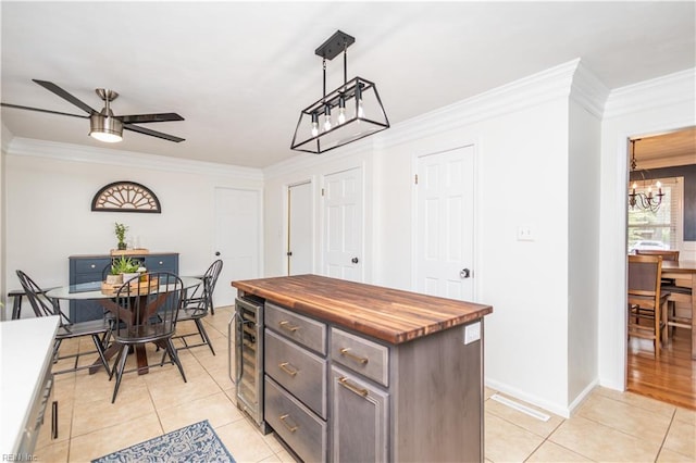 kitchen with wood counters, a chandelier, beverage cooler, crown molding, and light tile patterned floors