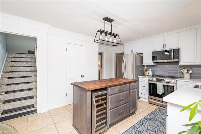 kitchen with appliances with stainless steel finishes, wine cooler, wooden counters, white cabinets, and light tile patterned floors