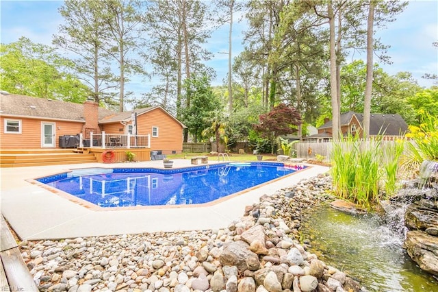 view of pool with a wooden deck, a fenced backyard, and a hot tub