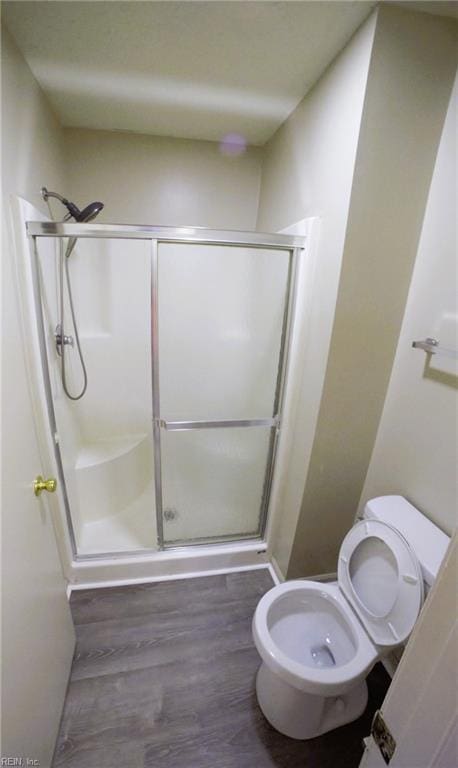 full bathroom with a shower stall, toilet, and wood finished floors