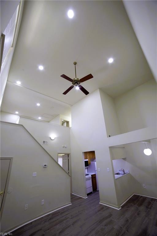 unfurnished living room with a high ceiling, ceiling fan, and wood finished floors
