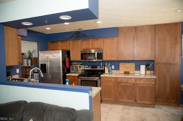 1132 Van Loen Dr, Virginia Beach, VA 23453 - kitchen with stainless steel appliances, a sink, recessed lighting, brown cabinetry, and light countertops