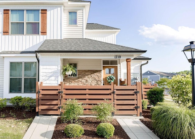 1710 Union Pacific Way, Suffolk, VA 23435 - view of front facade featuring a gate, a shingled roof, board and batten siding, covered porch, and stone siding
