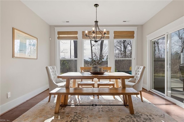 dining room with a chandelier, baseboards, and light wood-type flooring
