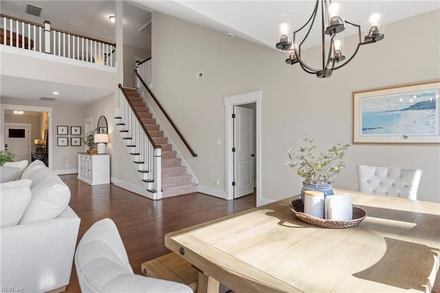 dining space with stairway, high vaulted ceiling, a chandelier, wood finished floors, and baseboards