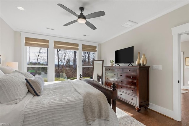 bedroom featuring wood finished floors, crown molding, baseboards, and a ceiling fan