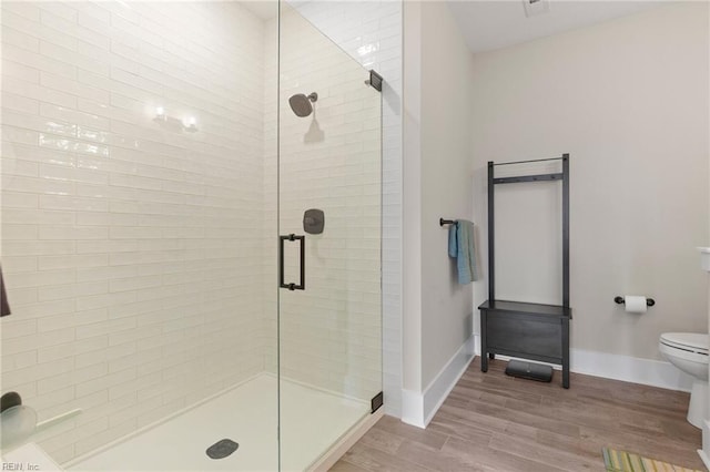bathroom with a shower stall, wood finished floors, toilet, and baseboards