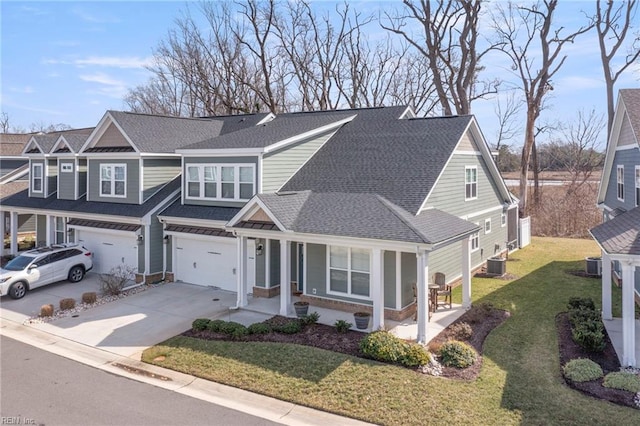 traditional-style home with concrete driveway, central AC, an attached garage, and roof with shingles