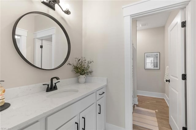 bathroom with wood finished floors, vanity, and baseboards