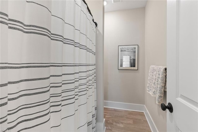 full bathroom featuring wood finished floors and baseboards