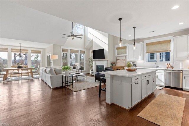 kitchen featuring stainless steel dishwasher, a sink, open floor plan, a glass covered fireplace, and recessed lighting