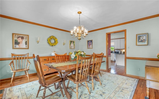 dining area featuring a chandelier, ornamental molding, wood finished floors, and baseboards
