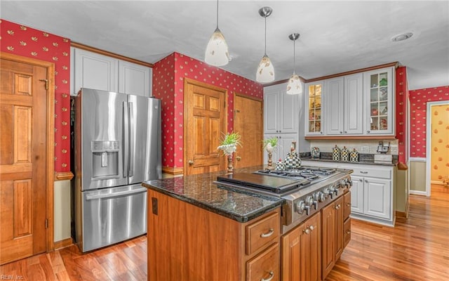 kitchen with stainless steel appliances, wallpapered walls, light wood-type flooring, a kitchen island, and baseboards